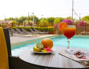 a table with a plate of fruit and a glass of juice at KAKTUS Hotel Volga - Adults Recommended in Calella