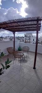 a patio with three benches and a wooden pergola at Suite Alborelli in Alberobello
