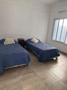 two beds in a room with a tile floor at Saladillo House in Saladillo