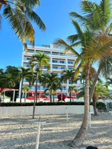 een gebouw op het strand met palmbomen op de voorgrond bij Boca Beach Residence 202 in Boca Chica