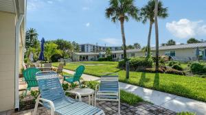 a group of chairs sitting on a patio with palm trees at Jamaica Royale #40 - 3 Heated Pools on the Beach! in Siesta Key