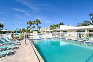 a swimming pool with chairs and a building at Jamaica Royale #40 - 3 Heated Pools on the Beach! in Siesta Key