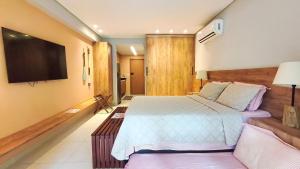 a bedroom with a bed and a flat screen tv at Studio no Eco Resort Praia dos Carneiros - Serviços de Limpeza Diária in Tamandaré