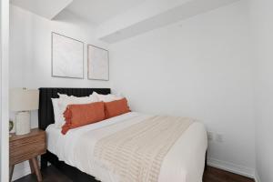a white bedroom with a bed with orange pillows at Bright 2BR Downtown Toronto Condo in Toronto
