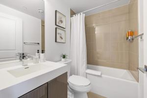 a bathroom with a toilet and a sink and a tub at Bright 2BR Downtown Toronto Condo in Toronto
