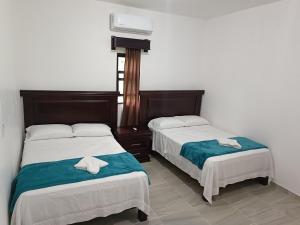 deux lits dans une chambre d'hôtel avec des serviettes dessus dans l'établissement Villa El Lago en Villas Camino Real cerca de las dunas de Chachalacas, à Ursulo Galván