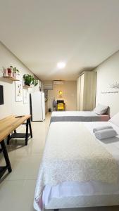 ein Schlafzimmer mit zwei Betten und eine Küche mit Kühlschrank in der Unterkunft 700m da Praia de Atalaia com ar e piscina in Santa Maria