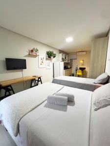 2 Betten in einem Zimmer mit einem Schreibtisch und einem TV in der Unterkunft 700m da Praia de Atalaia com ar e piscina in Santa Maria