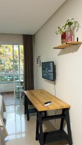 ein Zimmer mit einem Holztisch und einem Fernseher an der Wand in der Unterkunft 700m da Praia de Atalaia com ar e piscina in Santa Maria