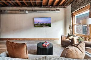 a living room with a couch and a tv on a wall at Soaring Designer Ceiling Condo near Market Square in Knoxville