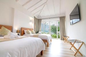 zwei Betten in einem weißen Zimmer mit Fenster in der Unterkunft Familiares casas de campo con vista increíble in Villa de Leyva