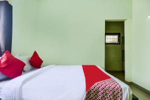 a bedroom with a bed with red and white pillows at Hotel O Aruthraa Residency in Coimbatore