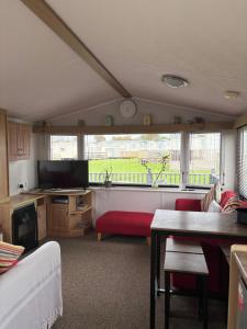 ein Wohnzimmer mit einem roten Sofa und einem Fernseher in der Unterkunft Family-Friendly 3-Bed Caravan Recently Renovated on Seven Bays Holiday Park, Padstow in Saint Merryn