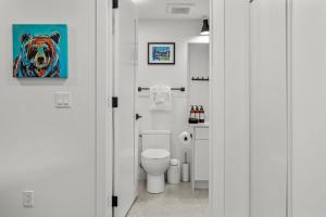 a bathroom with a toilet and a painting of a bear at Golden Escape 2 Bdrm Mountain VIEWS - managed by Little Sister Getaways in Canmore +37 photos