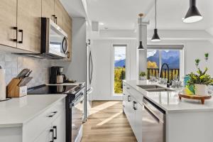 a kitchen with white cabinets and a large window at Golden Escape 2 Bdrm Mountain VIEWS - managed by Little Sister Getaways in Canmore