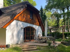Cabaña con techo de paja, mesa y sillas en Ferienhaus Boschhuys, en Uelsen