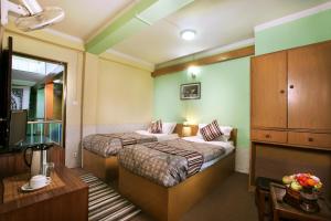 um quarto de hotel com duas camas e uma televisão em Hotel Nana em Catmandu