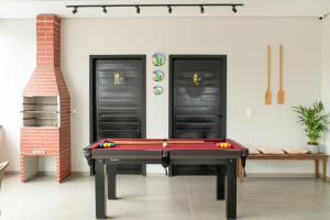 een pooltafel in een kamer met twee zwarte deuren bij Apto com Piscina e Churrasqueira Perto da Praia in São Bento