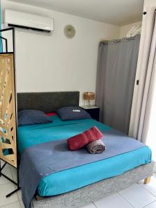 a bedroom with a bed with blue and red pillows at Studio - Résidence avec piscine in Sainte-Anne