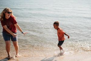 una donna e un bambino giocano nell'acqua della spiaggia di 4 Beachfront Cottages - New Bathrooms and Roofs a Lincoln Junction
