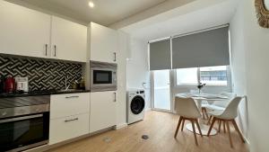 Una cocina con gabinetes blancos y una mesa y sillas. en Maxwell Apartments Quarteira, en Quarteira