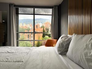 a bedroom with a white bed and a large window at Edificio La Frontera - Vista El Poblado Free Parking & Wifi Recep 24 h in Medellín +105 photos