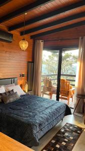 a bedroom with a large bed and a balcony at Vale Dourado Cabanas in Urubici