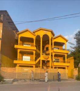 a yellow building with people standing in front of it at Paris High Muree Bhurban in Bhurban