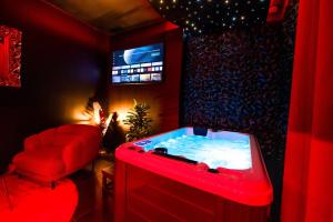 Una habitación roja con bañera de hidromasaje y televisión. en LOVE ROOM TOULOUSE - Centre, en Toulouse
