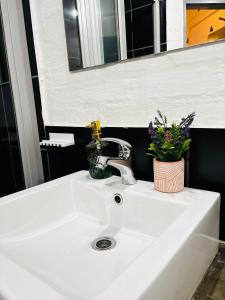 Un fregadero blanco con un grifo y flores. en Luu's Balcony, en Johannesburgo