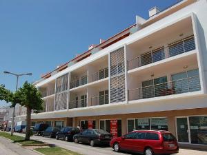 a large white building with cars parked in front of it at Apartamentos Mar de Alvor in Alvor