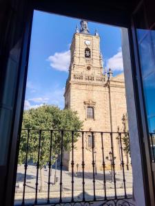 a building with a clock tower behind a fence at Los Soportales-Casa historica siglo XVI a 20 minutos de Puy du Fou in Orgaz