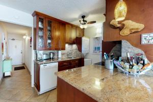 a kitchen with wooden cabinets and a marble counter top at Island Sands Resort 602 in Maalaea