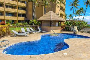 a swimming pool with lounge chairs and a building at Island Sands Resort 103 in Maalaea
