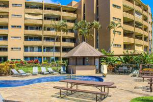 a hotel with a picnic table and chairs in front of a building at Island Sands Resort 103 in Maalaea