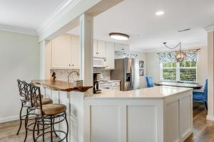 a kitchen with white cabinets and a island with chairs at Bethany Bay - 8004 Pettinaro Dr in Cedar Shores