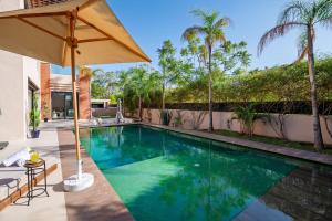 a swimming pool with an umbrella next to a house at Villa Anzar Refined Oasis wChef and Emerald Hammam in El Rhechat