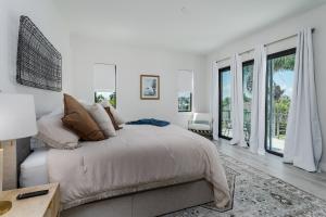 a white bedroom with a bed and large windows at Aloha Nani Hilo in Isles of Capri