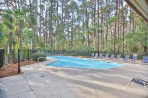 a swimming pool with chairs and a fence and trees at GL1205: 1205 Greenslake in Kiawah Island