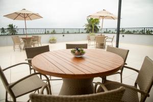 a wooden table and chairs in a patio with umbrellas at Apto com lazer Piscina, Jogos e Praia a 100m in São Bento