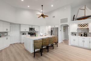 a kitchen with white cabinets and a ceiling fan at Island Twilight Delight in Marco Island