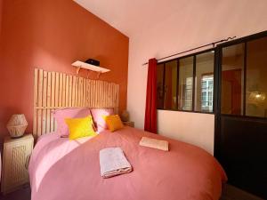 a bedroom with a large bed with yellow and pink pillows at Grand Place Arras RDC 4 pers vidéoprojecteur in Arras
