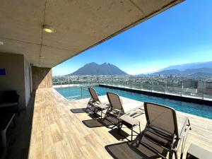 a group of chairs sitting on a balcony with a pool at Moderno y céntrico departamento en Monterrey in Monterrey