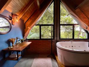 a large bathroom with a large tub and windows at Chalé com Hidromassagem em Garopaba in Palhocinha