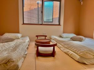 a room with two beds and a table and a window at 3F Ikebukuro Business District hotel, 9 mins to ST Max 4P 池袋商务区 全新装修 交通中心 车站9分钟 最大4人 直达新宿 涉谷 表参道 品川 池袋 上野 代代木 银座 原宿 in Katayama