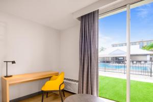 a bedroom with a desk and a yellow chair next to a window at B&B HOTEL Orlando International Drive near Universal - Newly Renovated! in Orlando