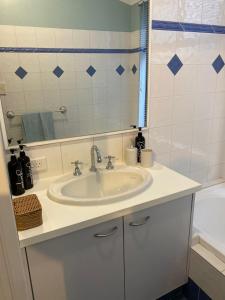 a bathroom with a sink and a mirror and a tub at Cheerful Sunny Garden Close Fremantle Netflix Wine in Hamilton Hill +18 photos