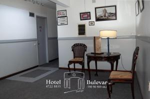 a room with two chairs and a table with a lamp at Hotel Bulevar in Paysandú