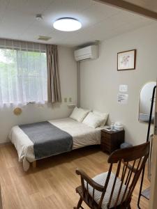 a bedroom with a bed and a chair and a window at ゲストハウス假穂 in Yoron +40 photos