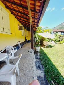 a patio with white tables and chairs and an umbrella at Hospedagem Casa do Bem Ficar in Lumiar